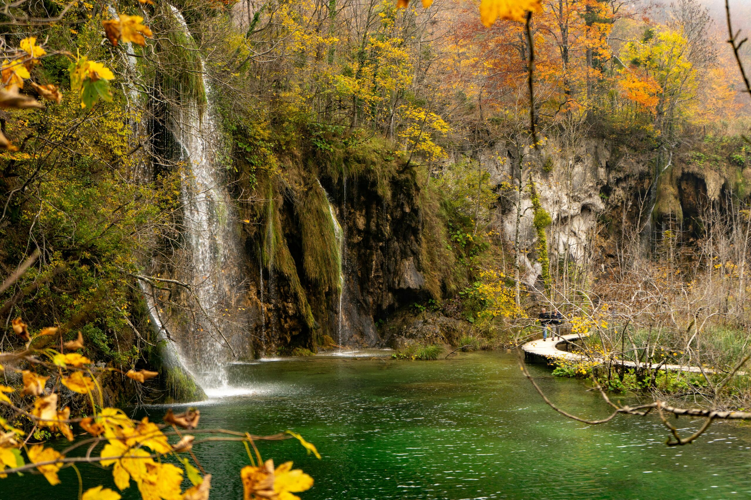 Enchanting view of a waterfall surrounded by fall foliage at Plitvice Lakes National Park, Croatia.